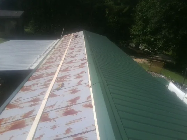 Old rusted panels beside newly installed green metal roofing — Wind Damage Roof Repair by Roofing Brothers in Mathews