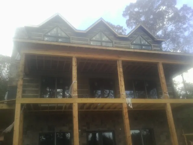 Dormers and porch framing on a large log home under construction — Roof Coating work by our crew in Mathews